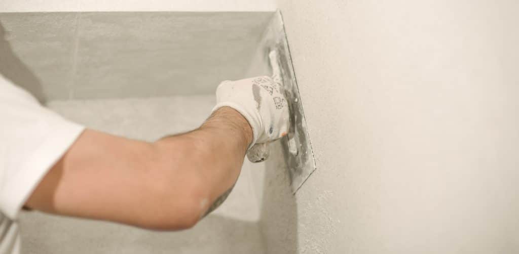 Construction worker plastering a wall with a spatula