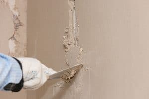 Hand with a spatula in the process of leveling the raw plaster.