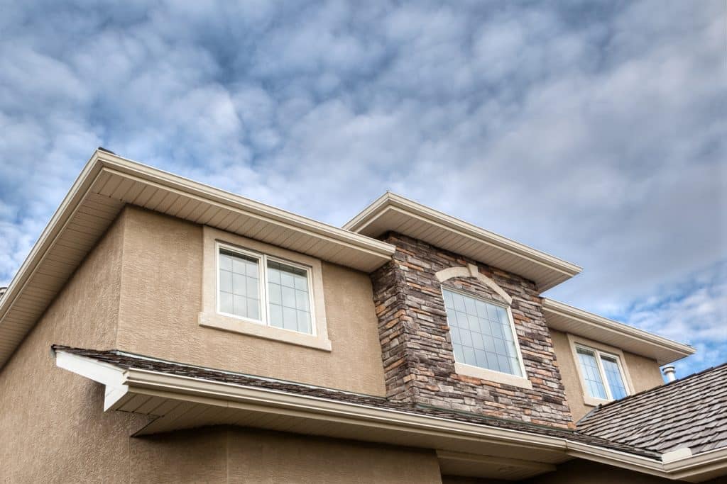 Roofline showing windows, brick stones, gutter, soffit, stucco