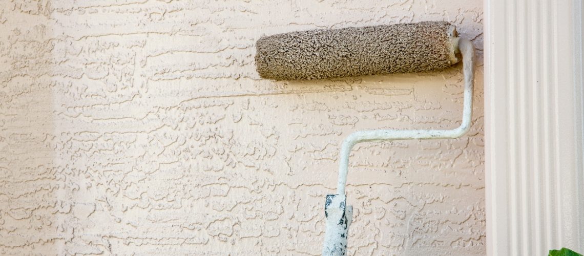 Paint roller attached to pole on outside wall of house