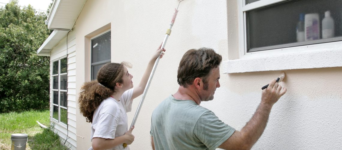 A family applying a coat of stucco onto a home