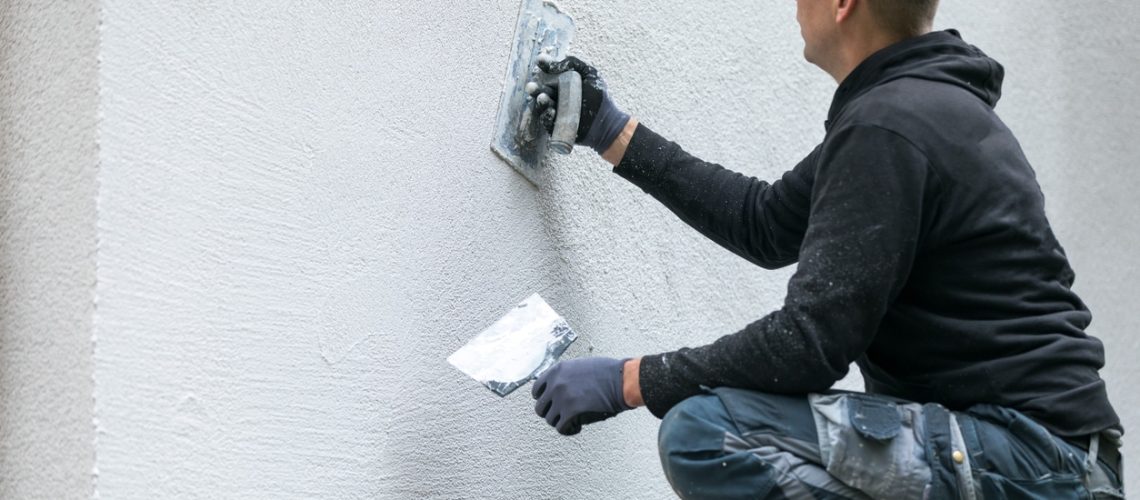 construction worker putting decorative plaster on house exterior